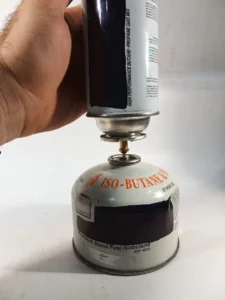 Detalle del adaptador de cartucho a bombona con rosca en proceso de trasvaso de gas