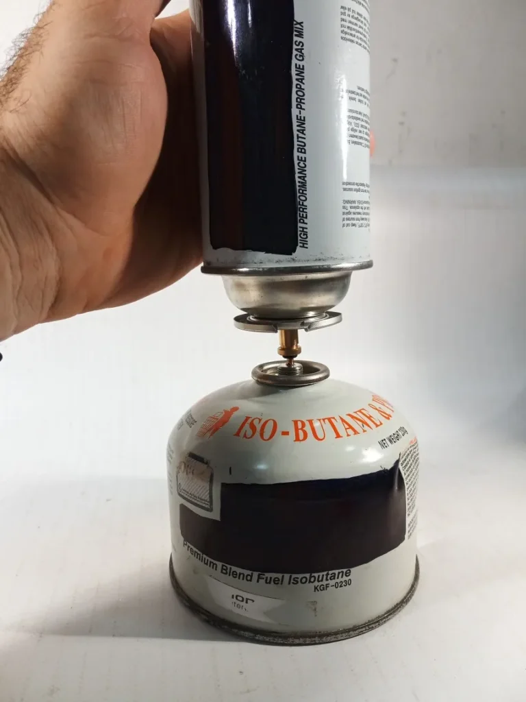 Detalle del adaptador de cartucho a bombona con rosca en proceso de trasvaso de gas